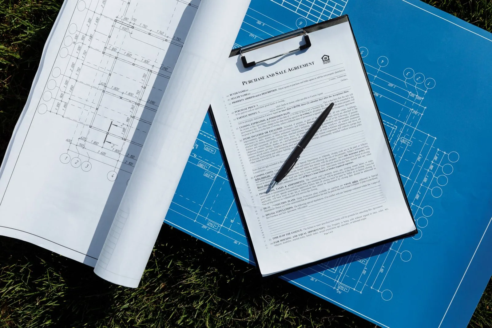 Contract op een klembord met bouwtekeningen
